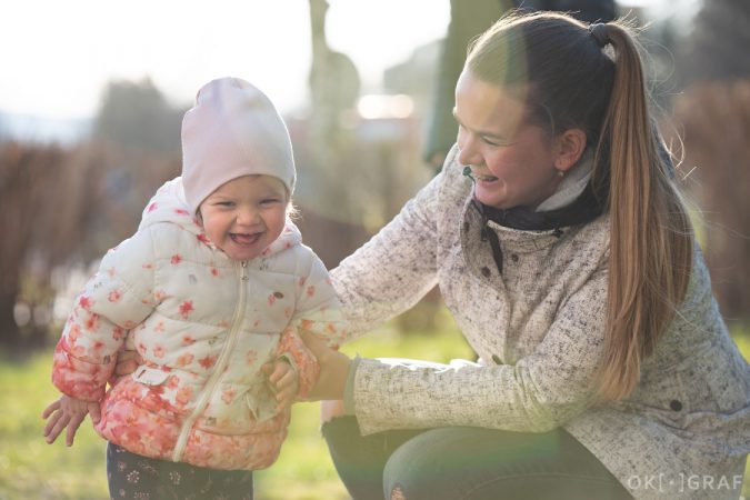 Rozesmátý portrét holčičky s maminkou v jarním slunci. Okograf. Pavla Bernardová.